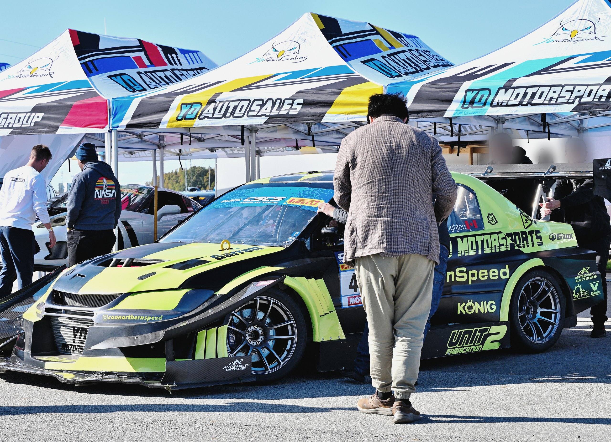 YD Auto Group, YD Auto Sales and YD Motorsports tents in the paddock at the Canadian Sport Compact Series time attack finale in October 2022, with the YD Motorsports-liveried Mitsubishi Lancer Evolution time attack car in front.