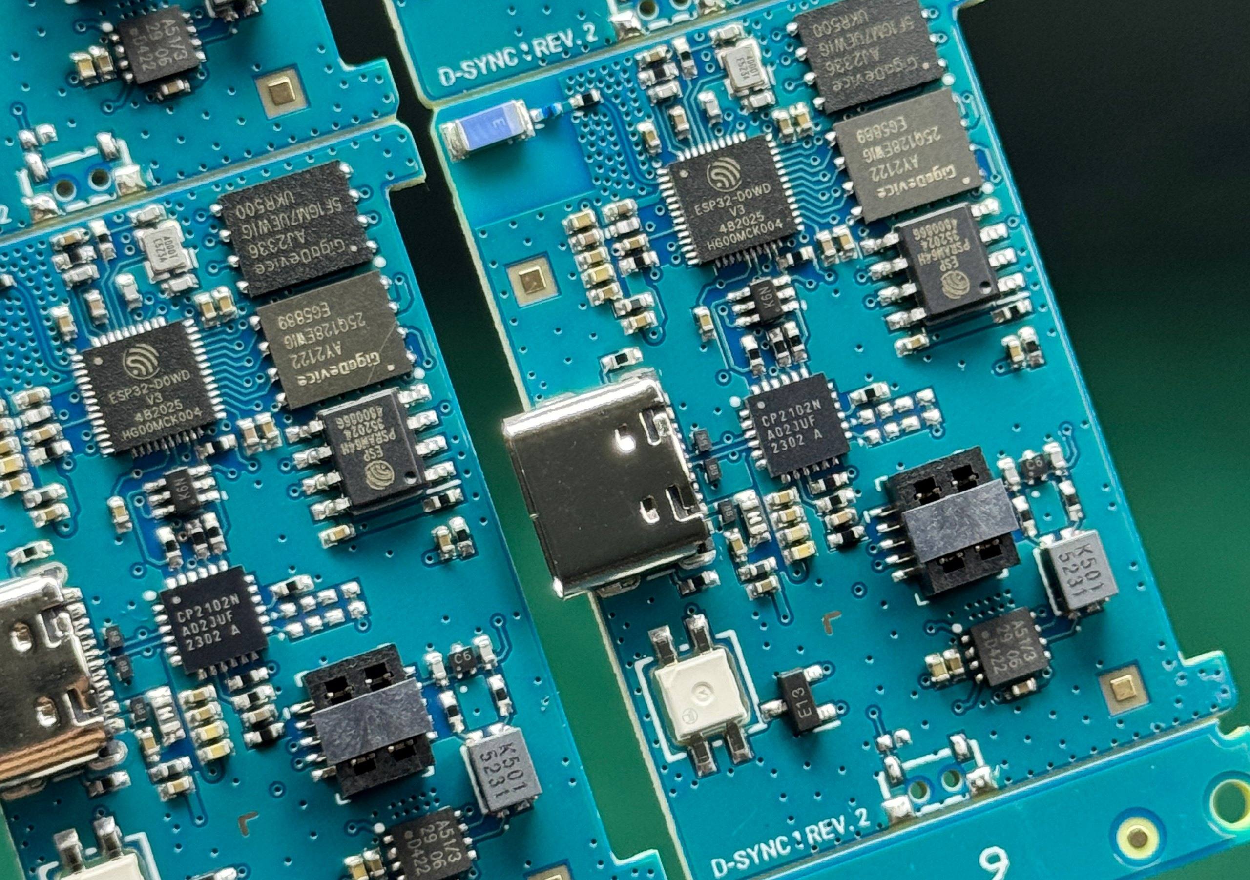 Close-up of D-Sync Rev. 2 circuit boards showing the ESP32 microcontroller, GigaDevice flash memory, CP2102N USB bridge and USB-C connector.